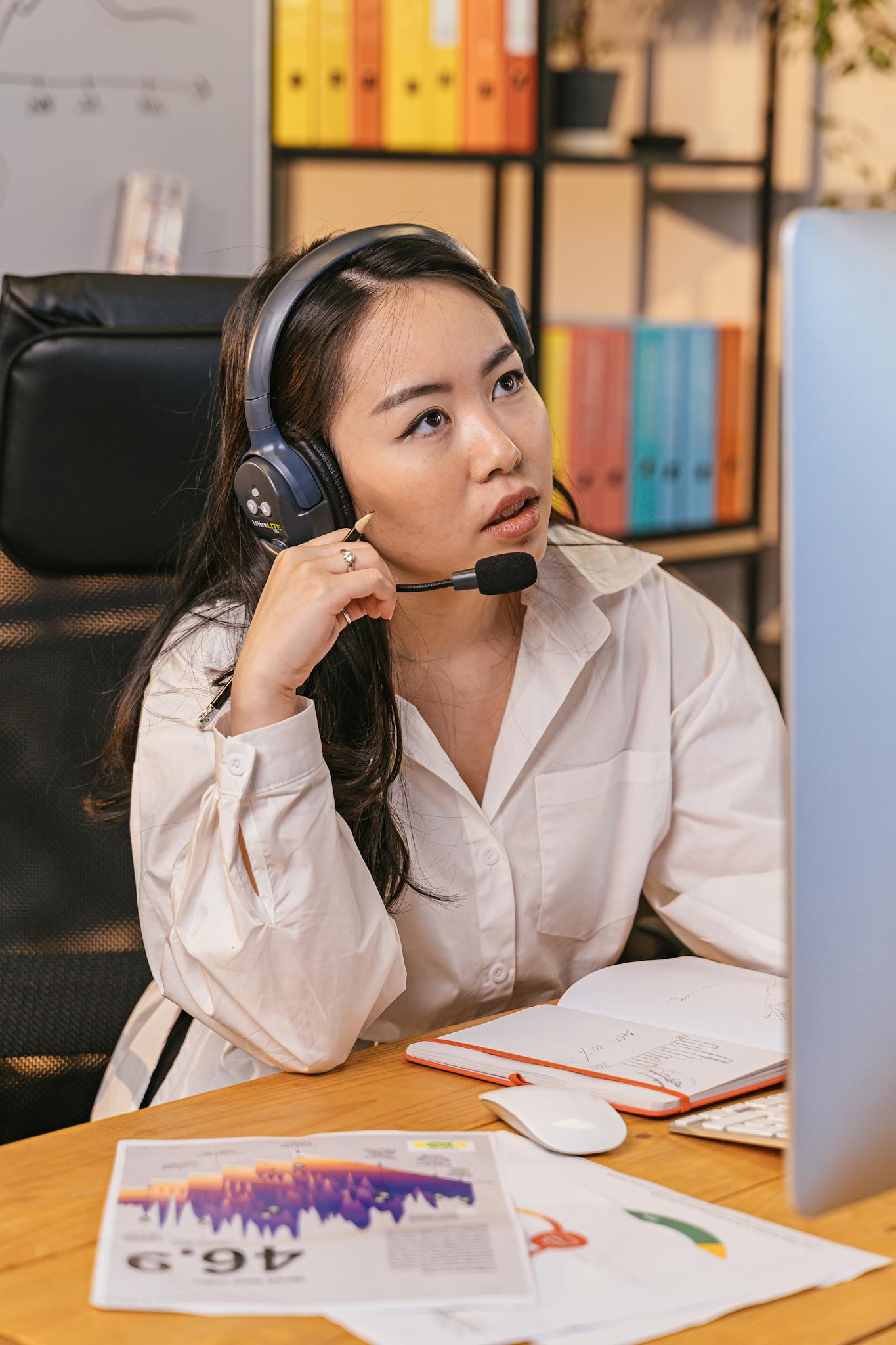 Focused businesswoman wearing a headset and working at her desk in a modern office environment.